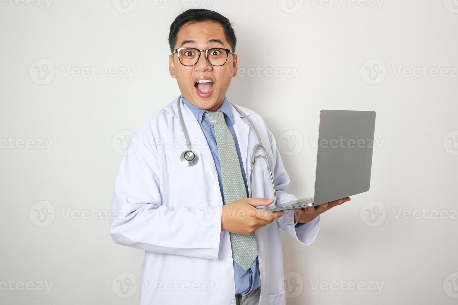 A professional senior Asian male doctor is working on his laptop computer in his office at the clinic, reading medical cases online or responding to emails. photo