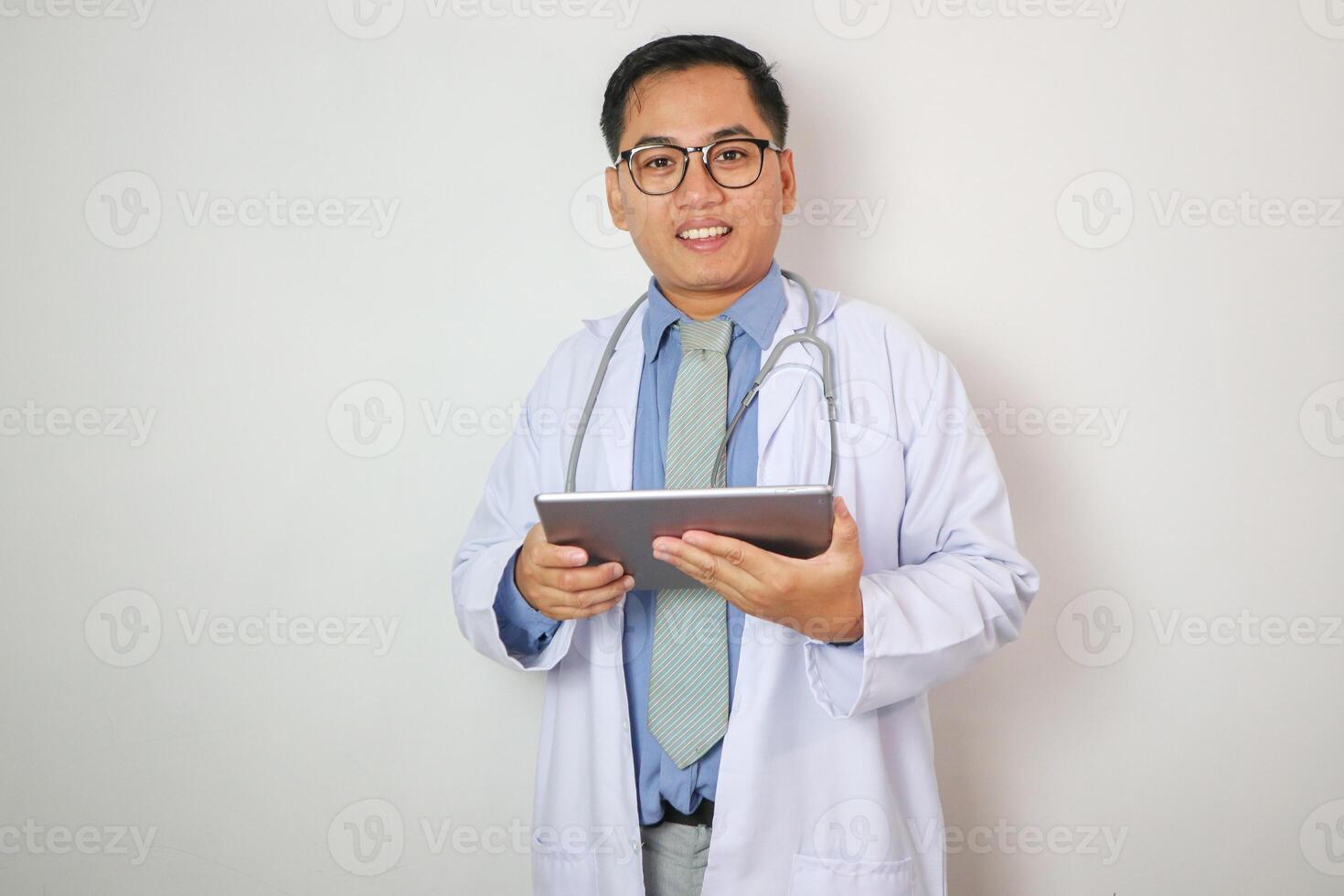 Portrait of southeast Asian male medical doctor using digital tablet computer, standing isolated on white photo