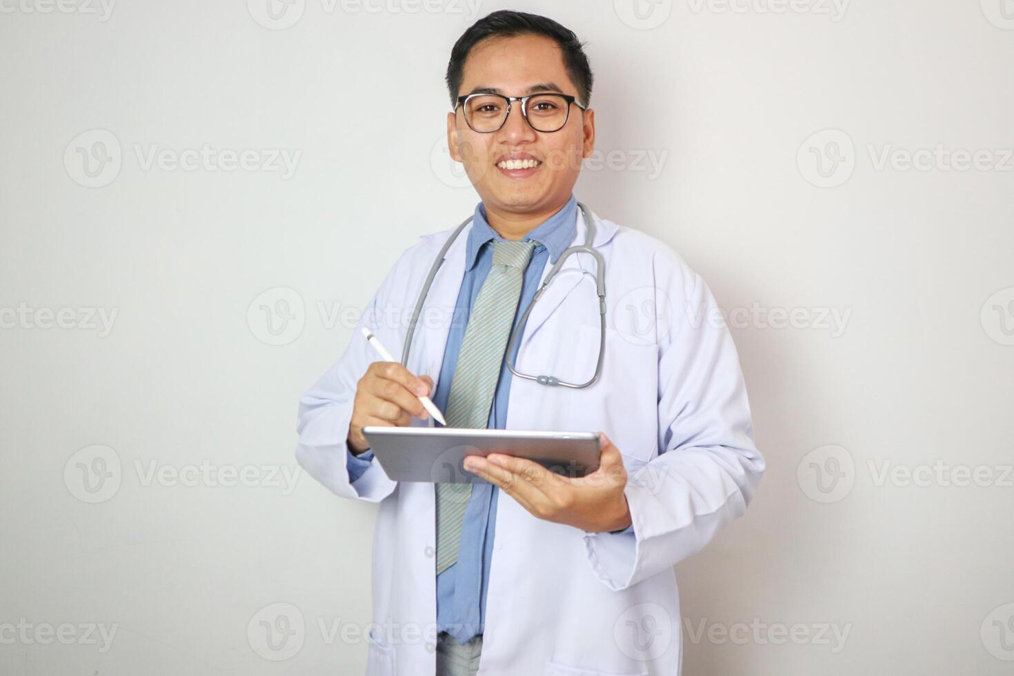 Male doctor smiling with happy face. Holding a computer tablet. photo