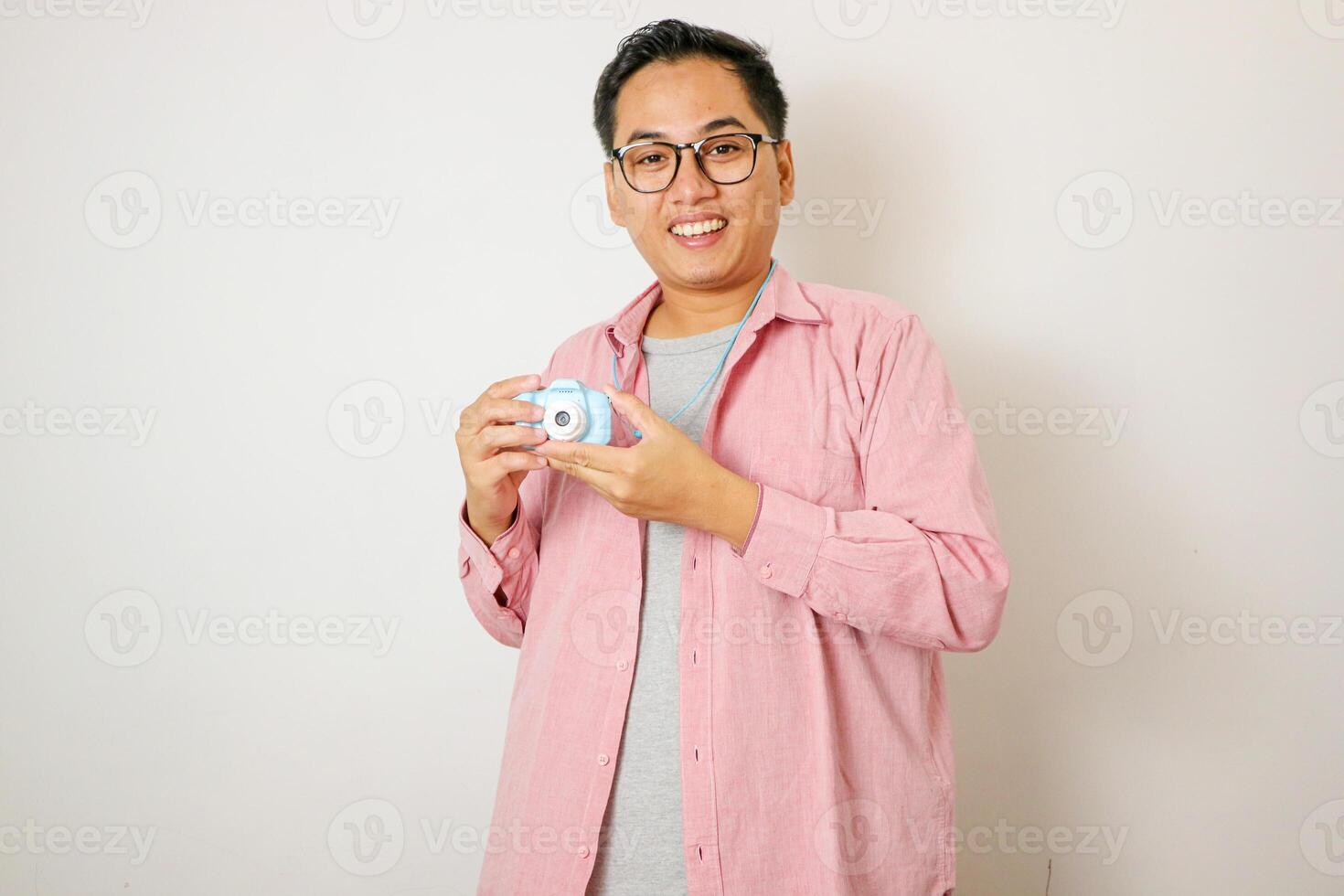 Handsome young photographer poses with smiles and holding professional digital camera in the studio. photo