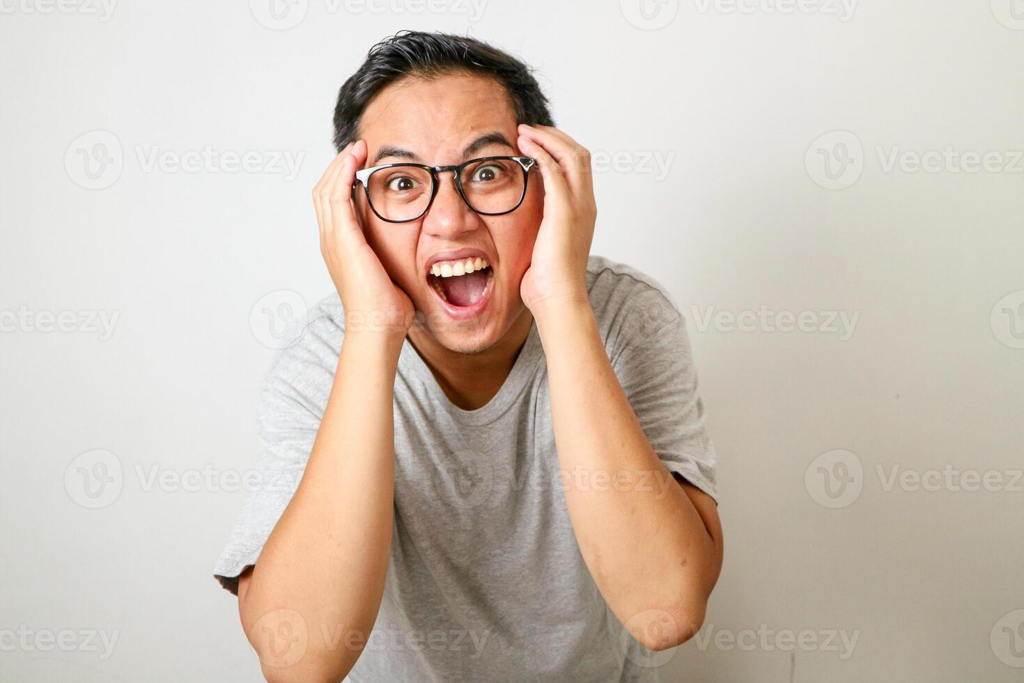 People, Human Emotions And Feelings Concept. Portrait of shocked scared Asian man with open mouth touching face and cheeks looking at camera in amazement, isolated over white studio wall photo