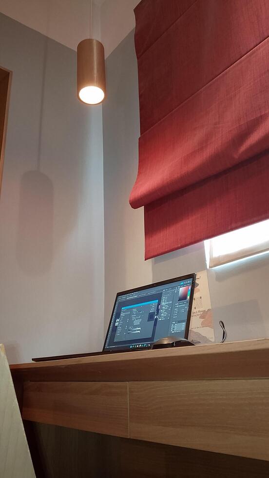 A laptop computer sitting on a desk in a room photo