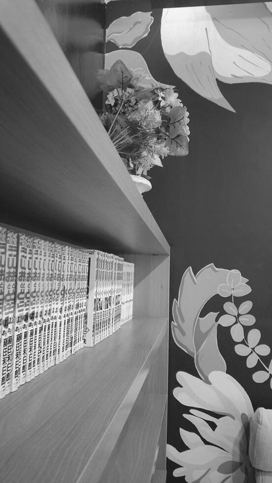 A black and white photo of a shelf with books on it