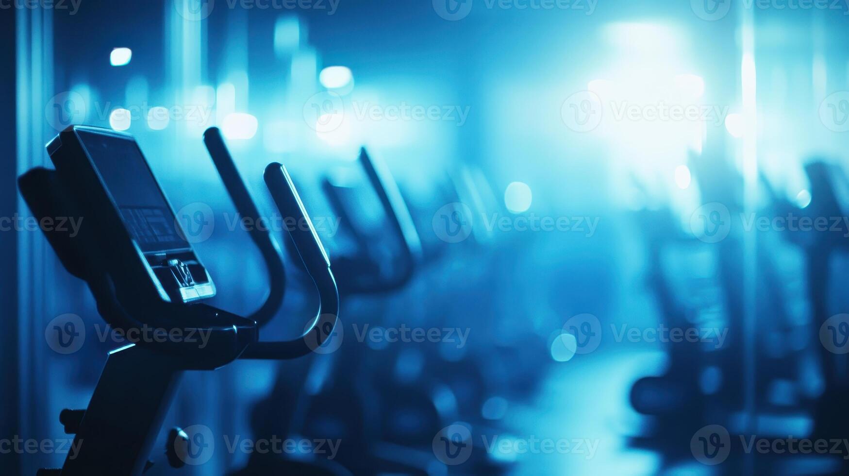A dimly lit gym with exercise bikes arranged in a row for fitness activities. photo