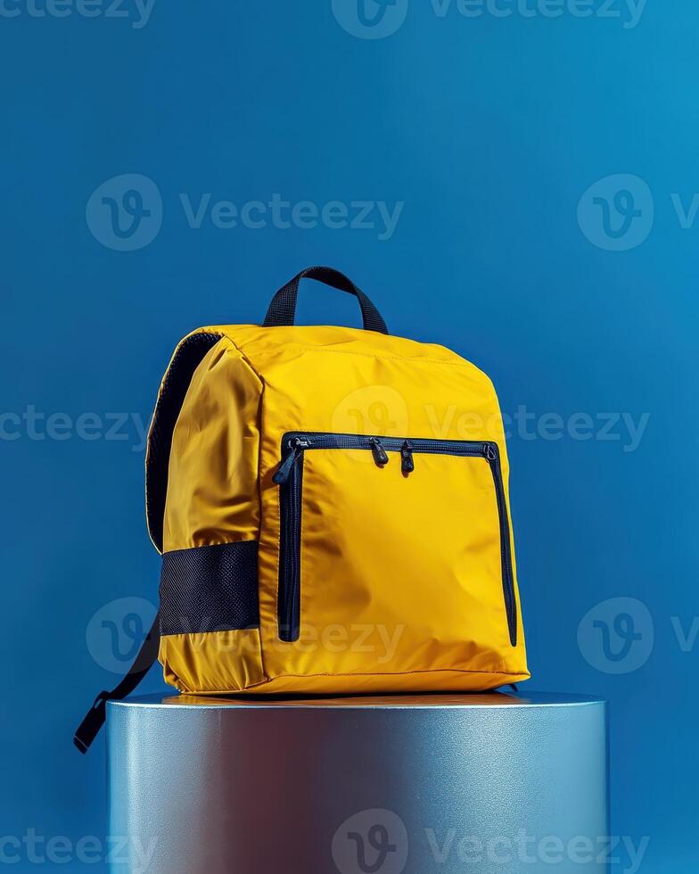 A bright yellow backpack on a pedestal against a blue background, showcasing modern design photo
