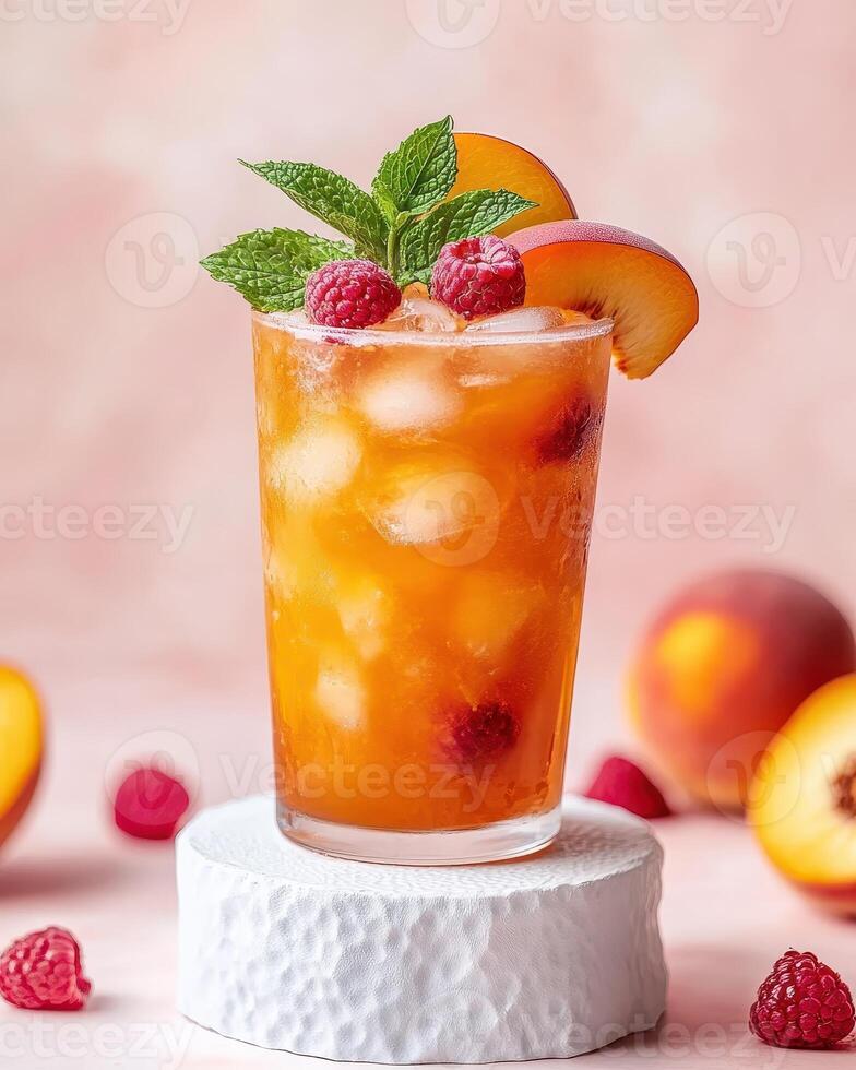 A refreshing peach and raspberry drink garnished with mint, served on a textured pedestal photo