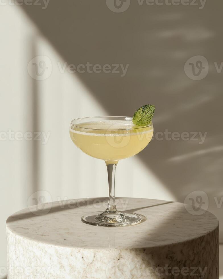 A refreshing cocktail garnished with a mint leaf, elegantly displayed on a marble surface. photo
