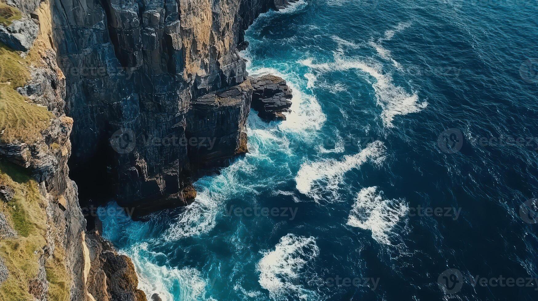Aerial view of rugged cliffs meeting turbulent ocean waves. photo