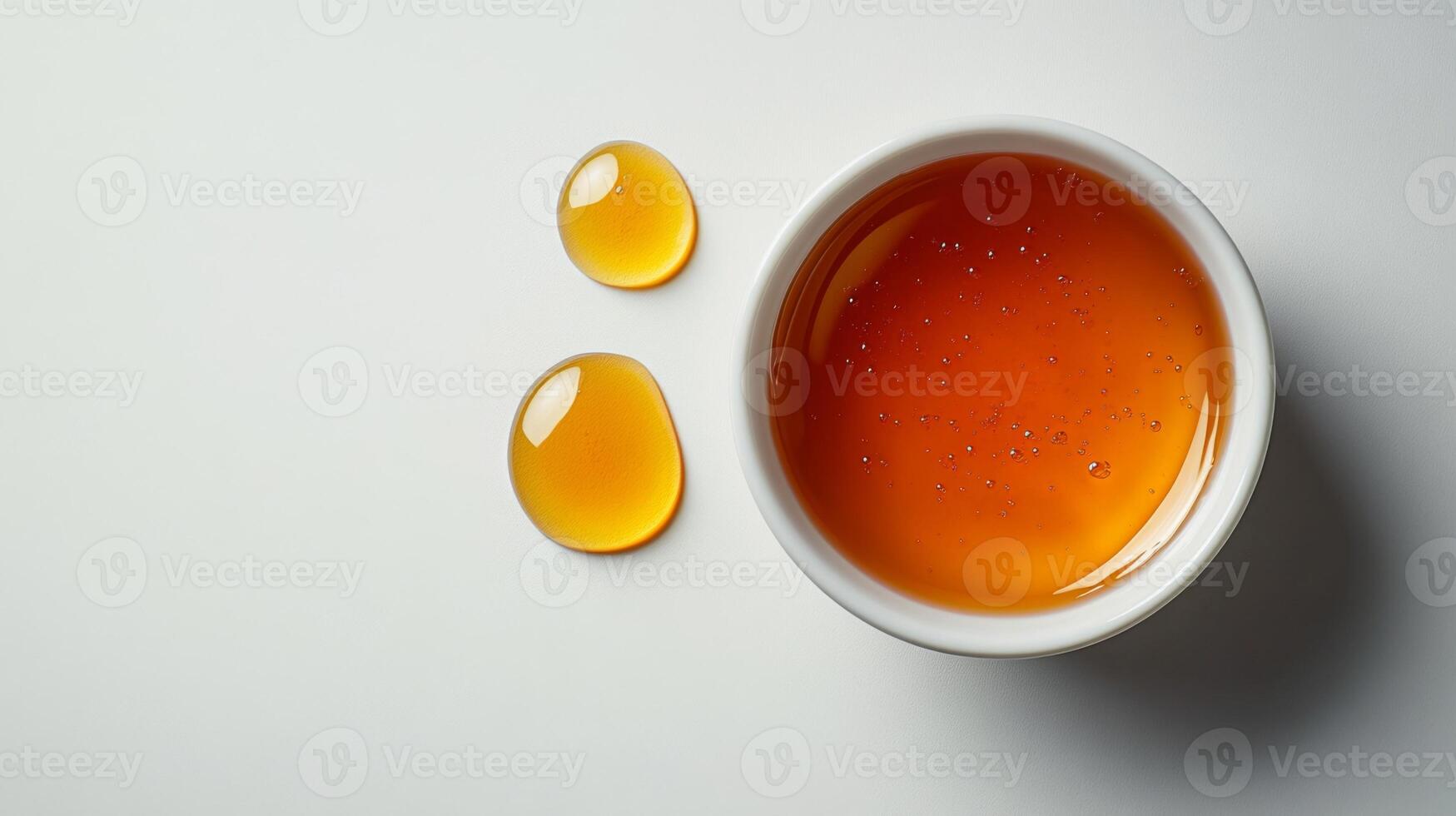 A bowl of orange liquid and two small drops of liquid photo