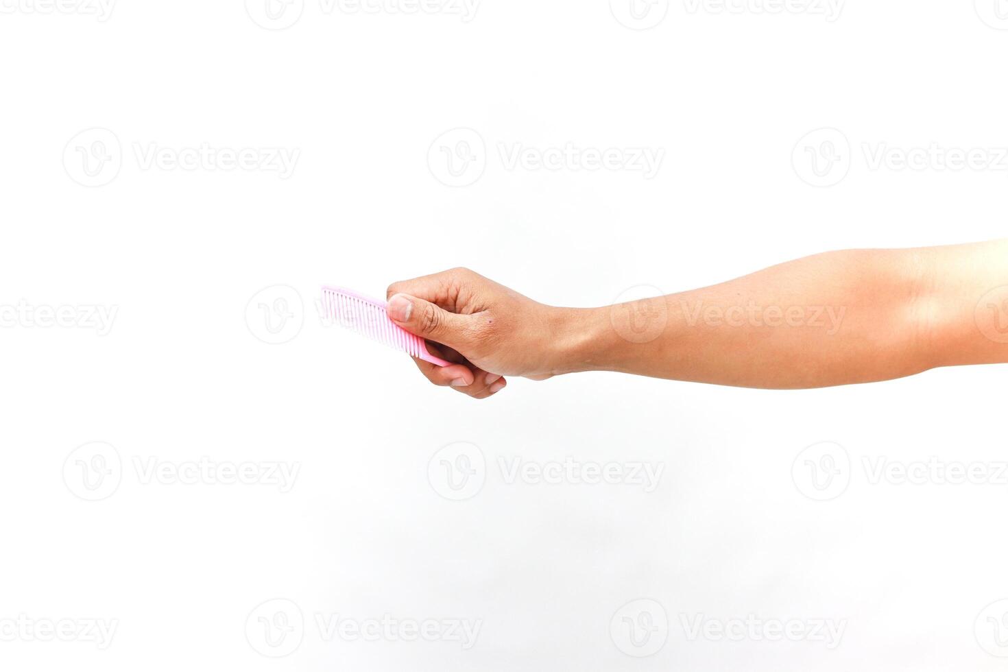 A close-up view of a person's arm holding a pink comb against white backdrop photo