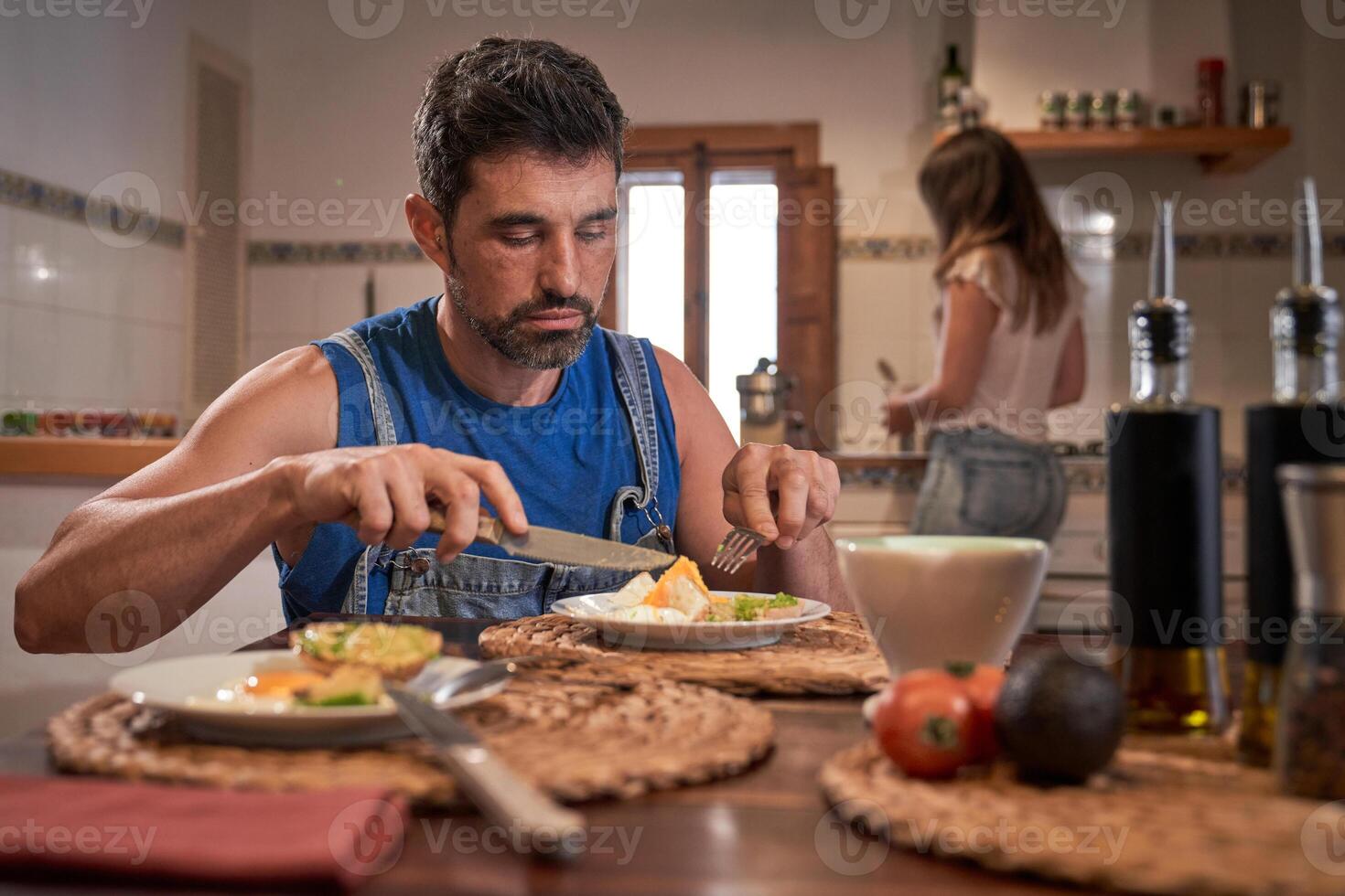 Serious man having breakfast at wooden table photo