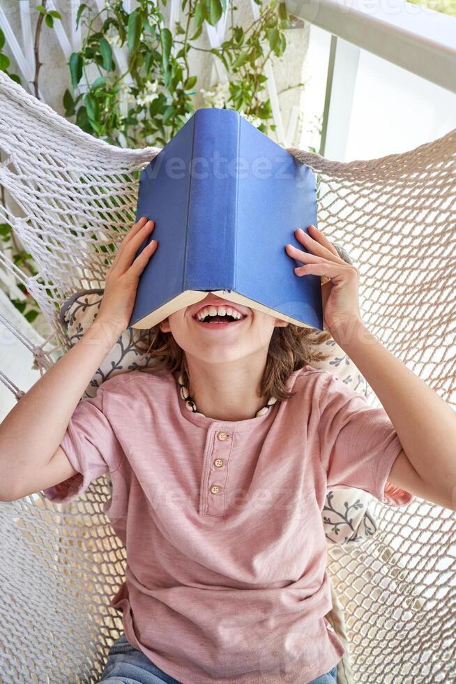 Unrecognizable boy lying in hammock with book on head photo