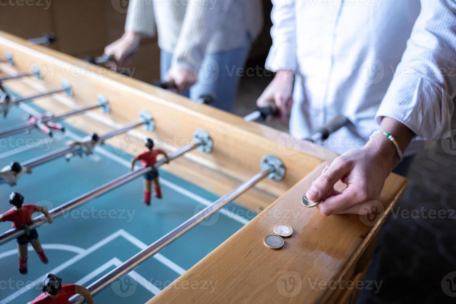 A young man is taking a euro coin to be used in the table football game photo