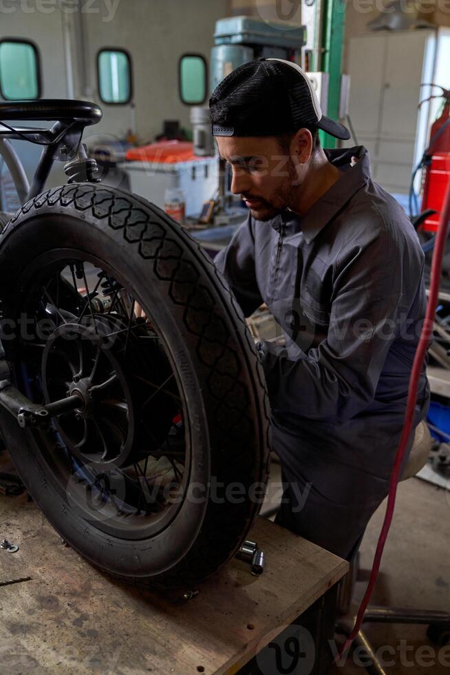 Concentrated male mechanic fixing motorbike wheel photo