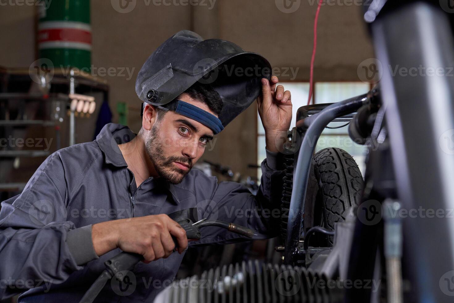 Focused mechanic working with welding machine in garage photo
