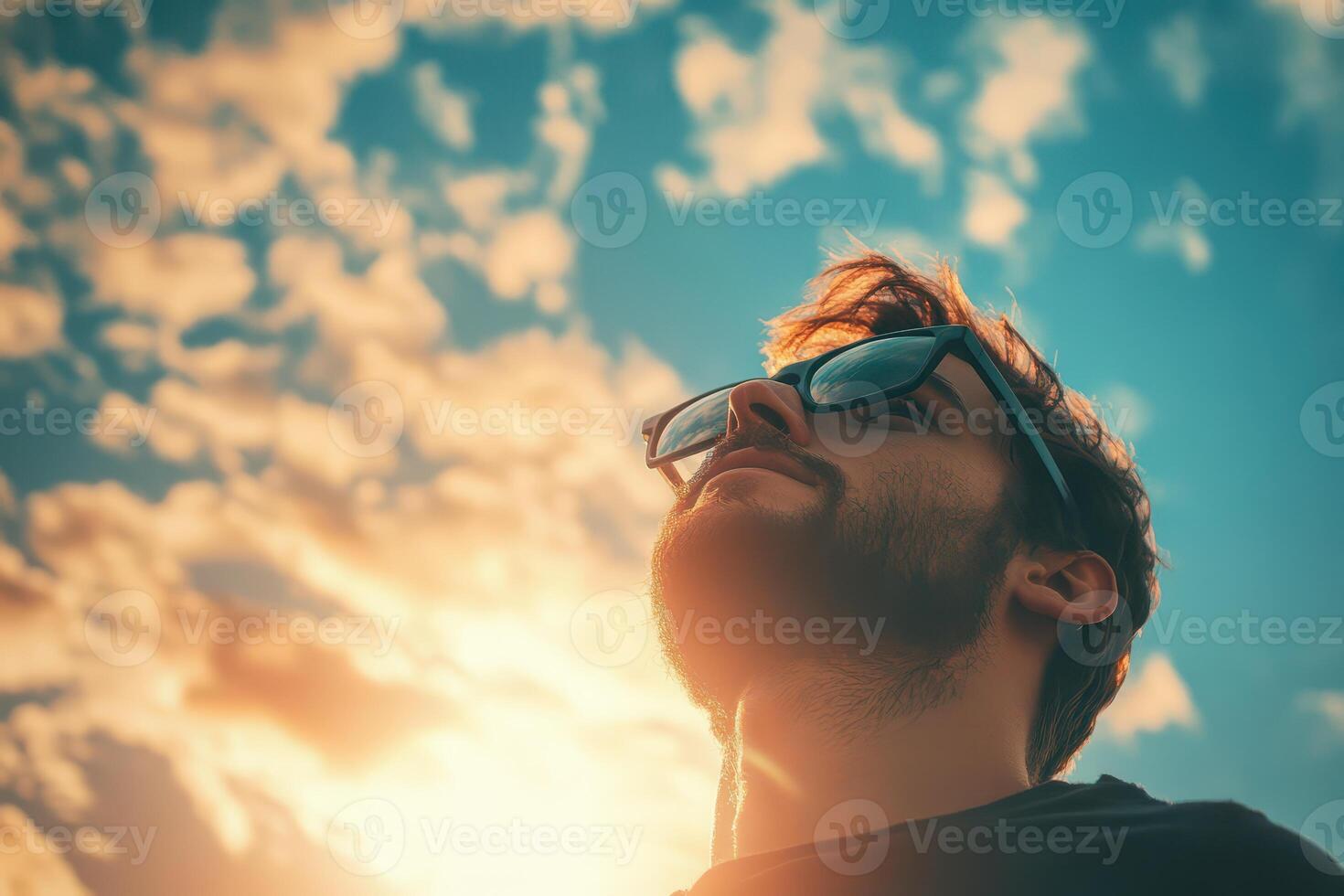 A man wearing sunglasses and looking up at the sky photo