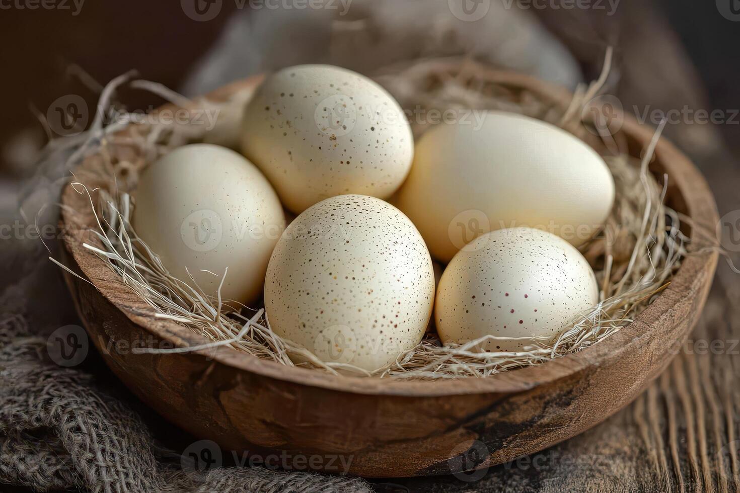 Five white eggs in a wooden bowl on a table photo
