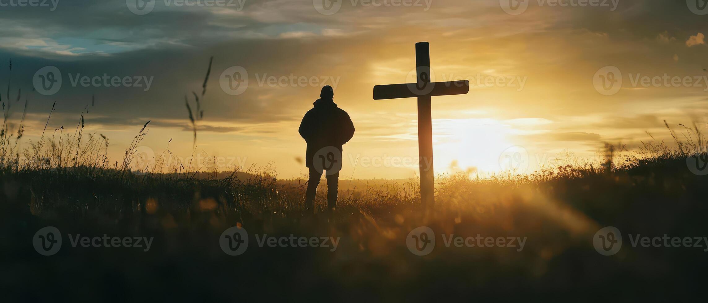A silhouette of a man standing in front of a cross photo