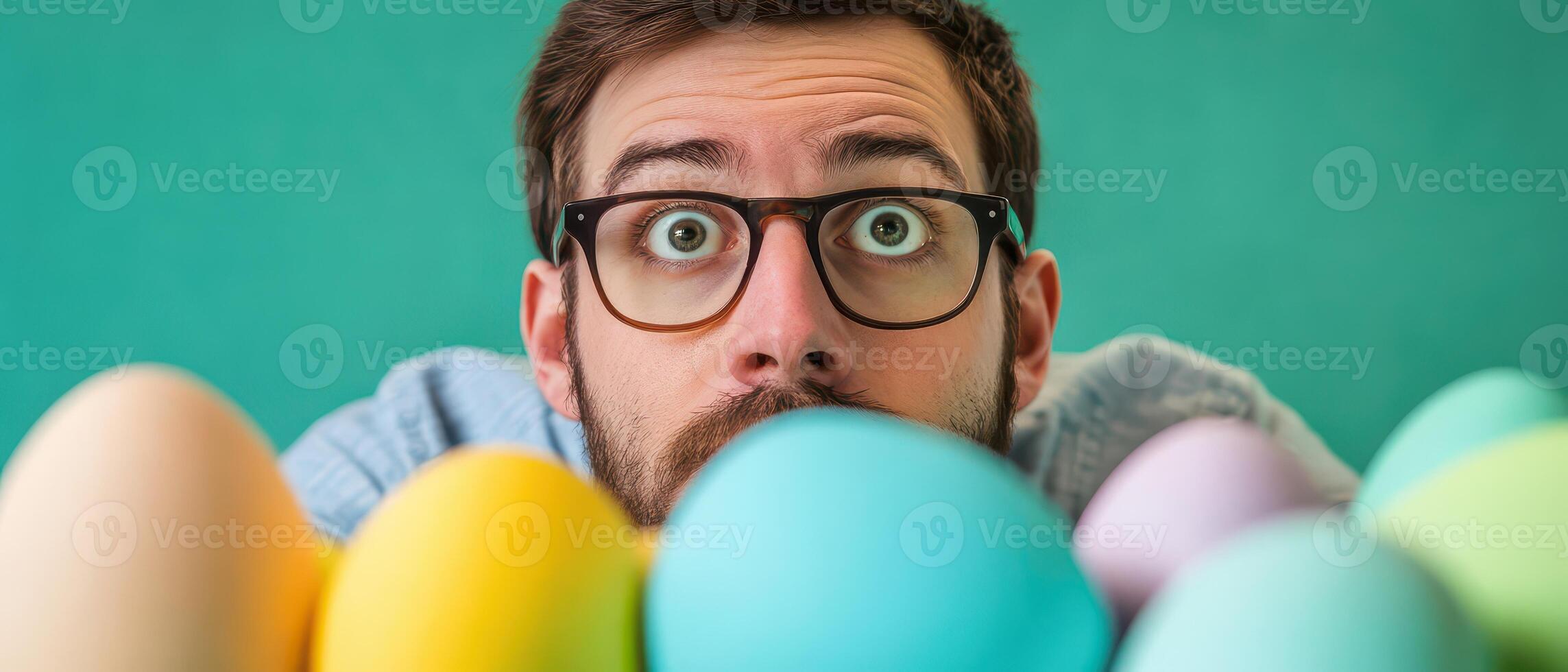 A man with glasses and a beard is looking at a group of colorful eggs photo