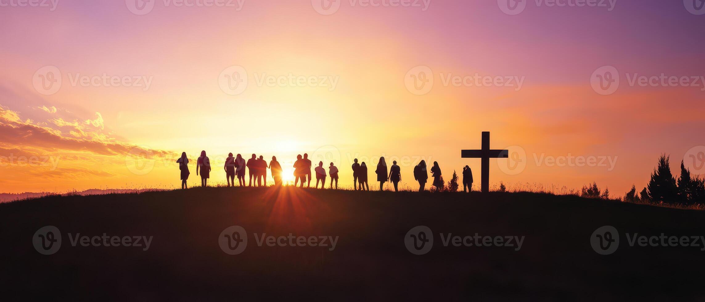 People standing on a hill at sunset with a cross in the background photo
