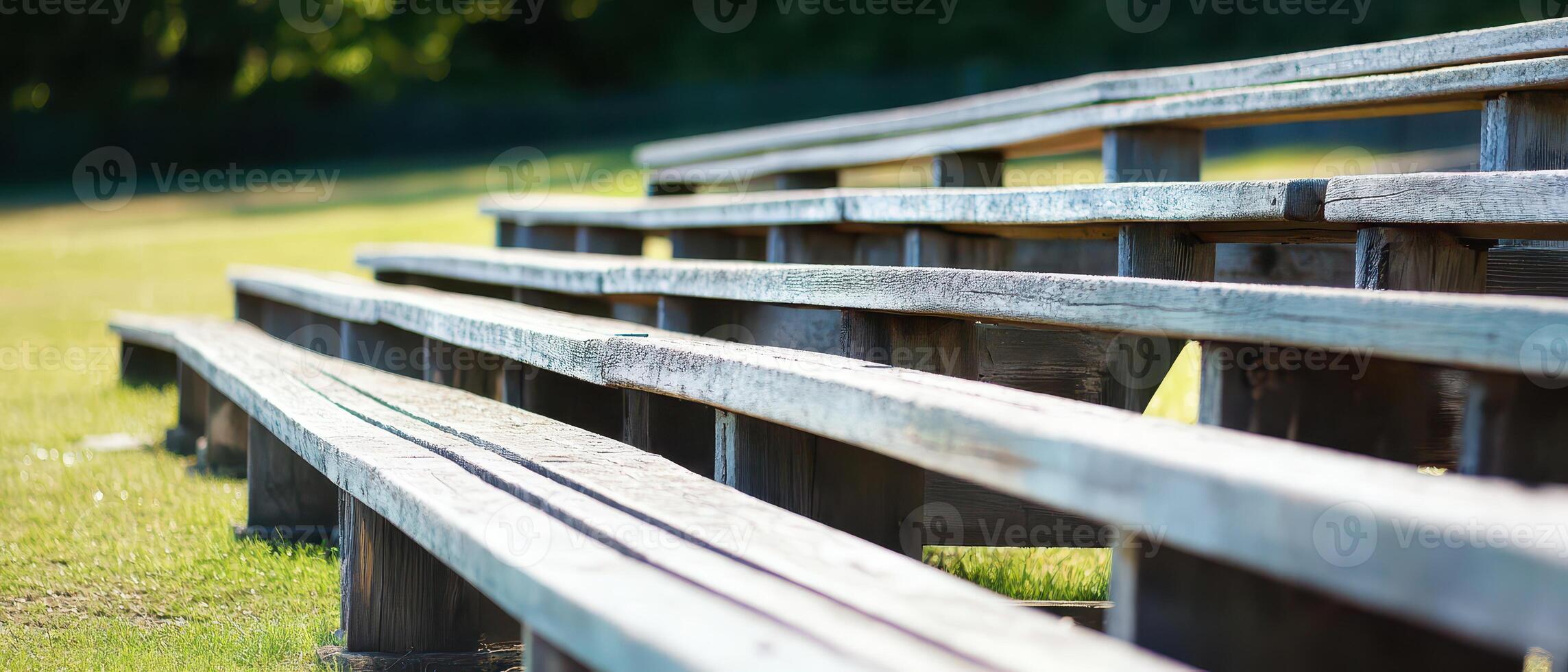 A row of wooden bleachers in a grassy field photo