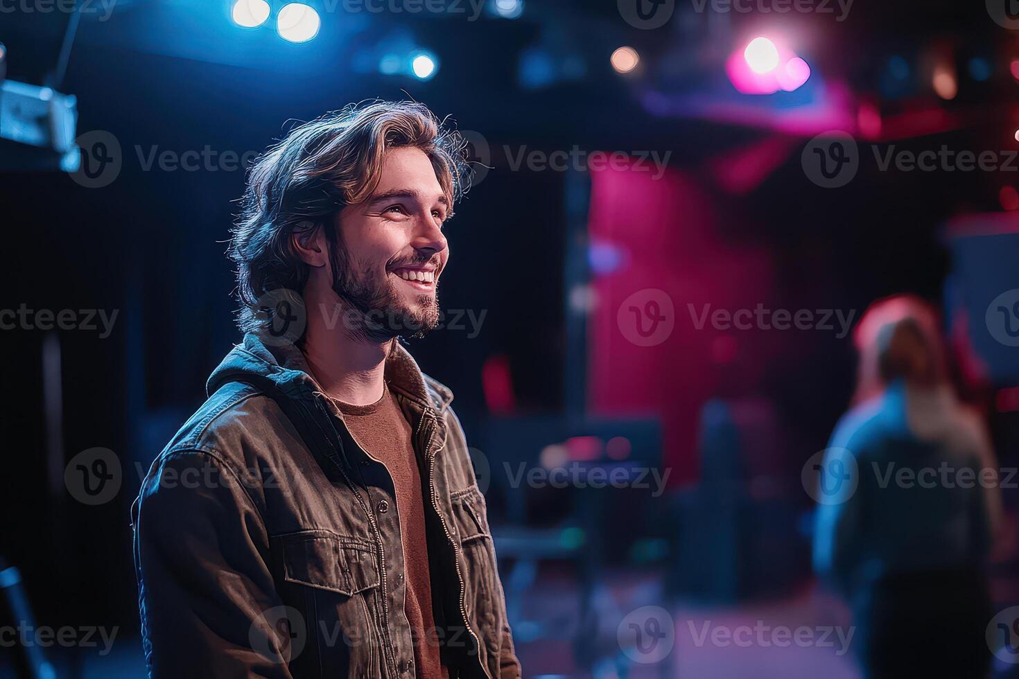 A man smiles while standing in front of a stage photo