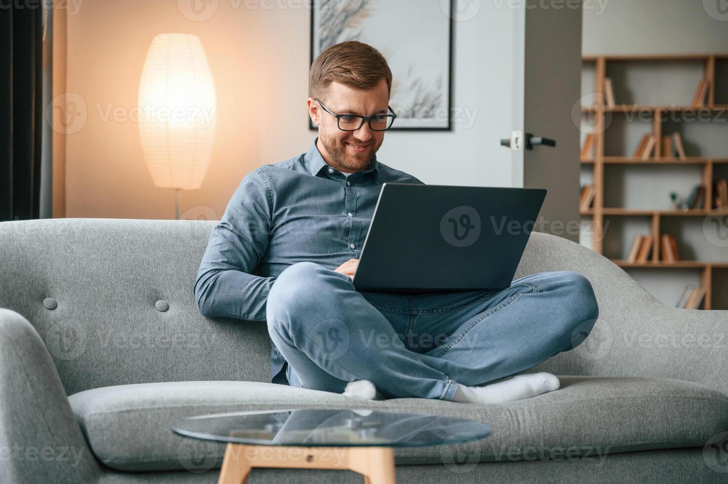 Male freelance worker in glasses ,is using laptop at home. Cozy apartment photo