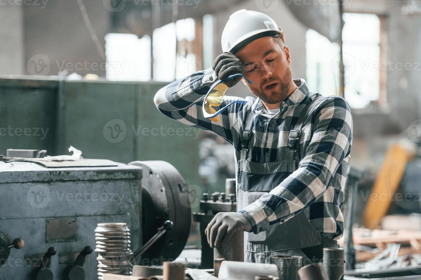 Tired, factory male worker in uniform is indoors photo