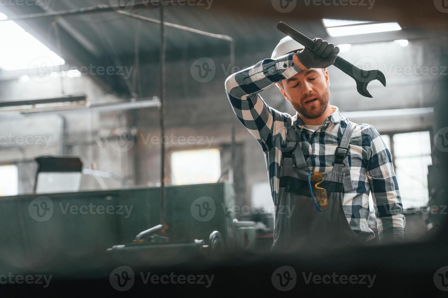 With wrench in hand. Factory ,male worker in uniform is indoors photo