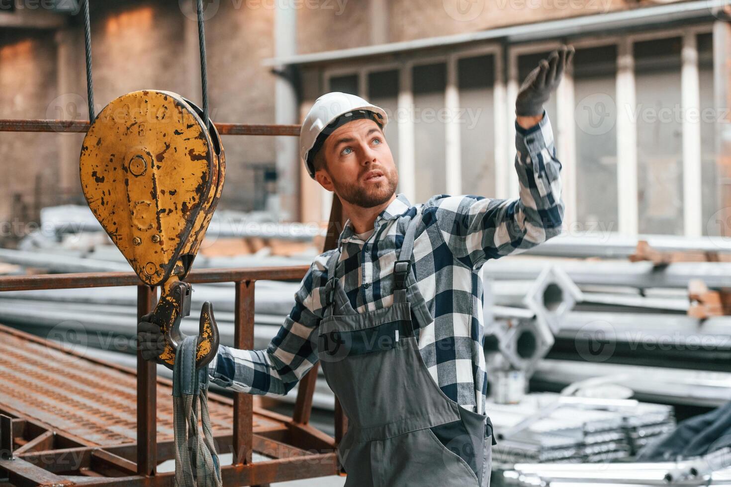 Communicate with crane operator.. Factory male worker in uniform is indoors photo