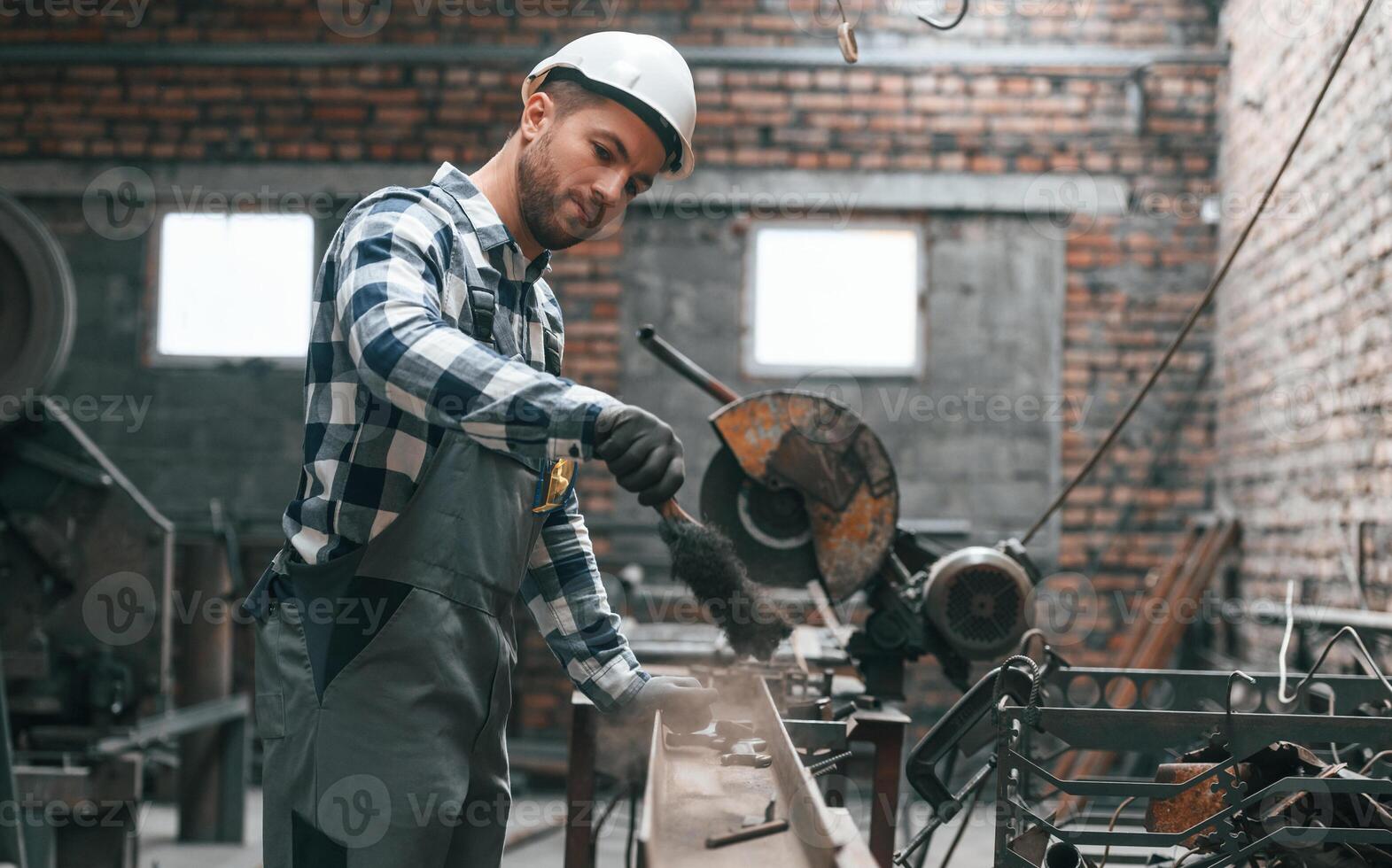 Working by, operating machine. Factory worker in uniform is indoors photo