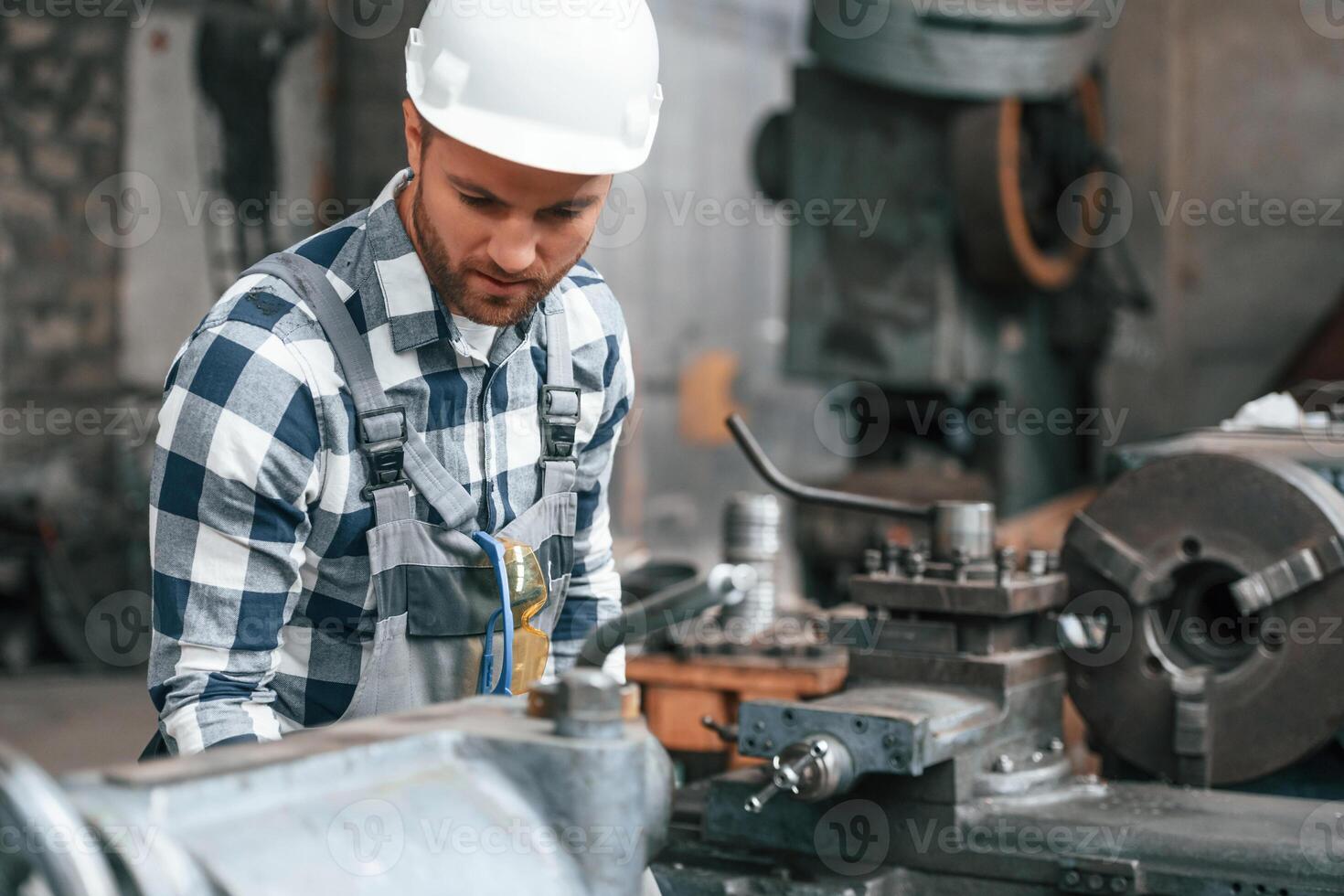 Working, by operating machine. .Factory worker in uniform is indoors photo