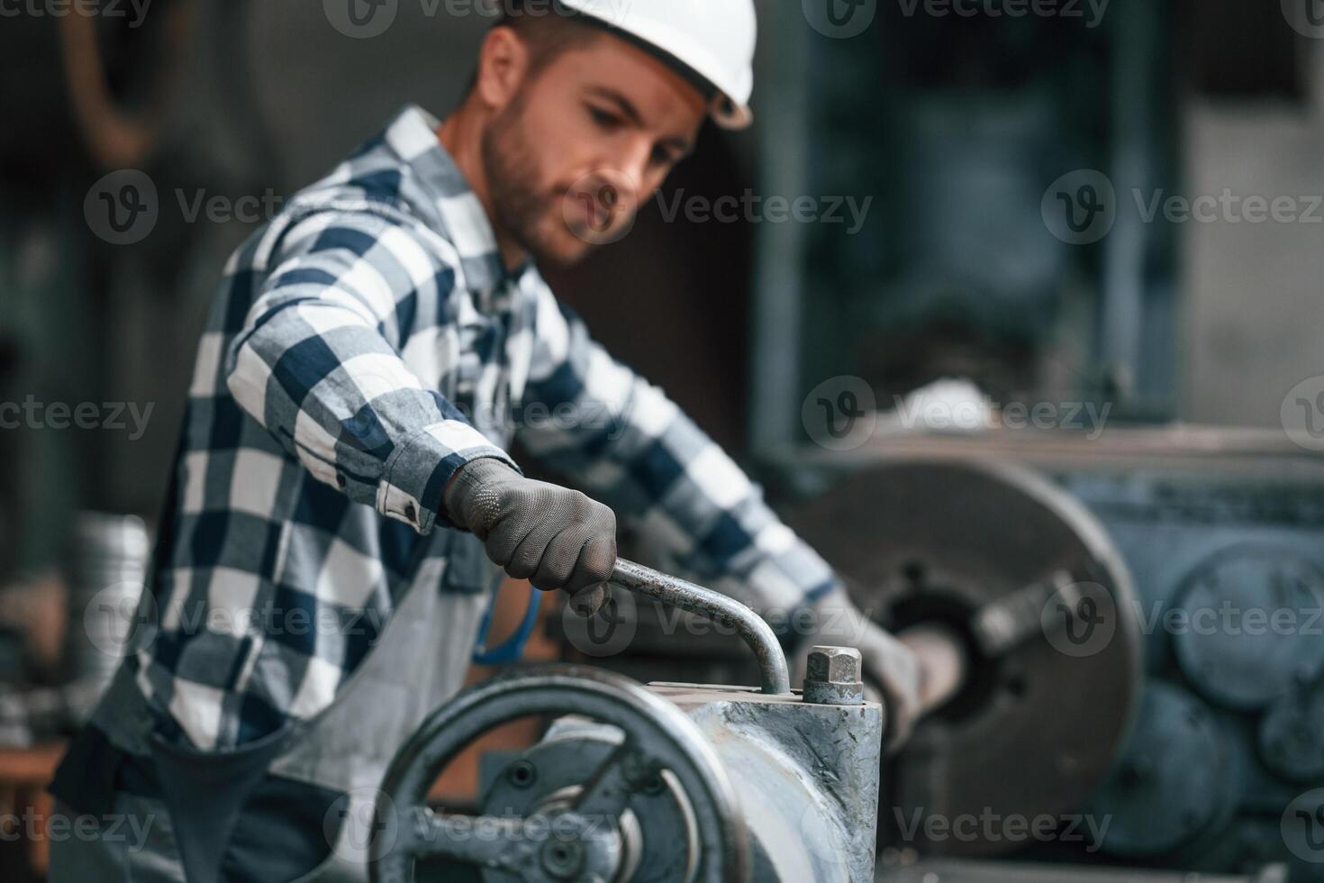 Working by ,operating machine. Factory worker in uniform is indoors photo