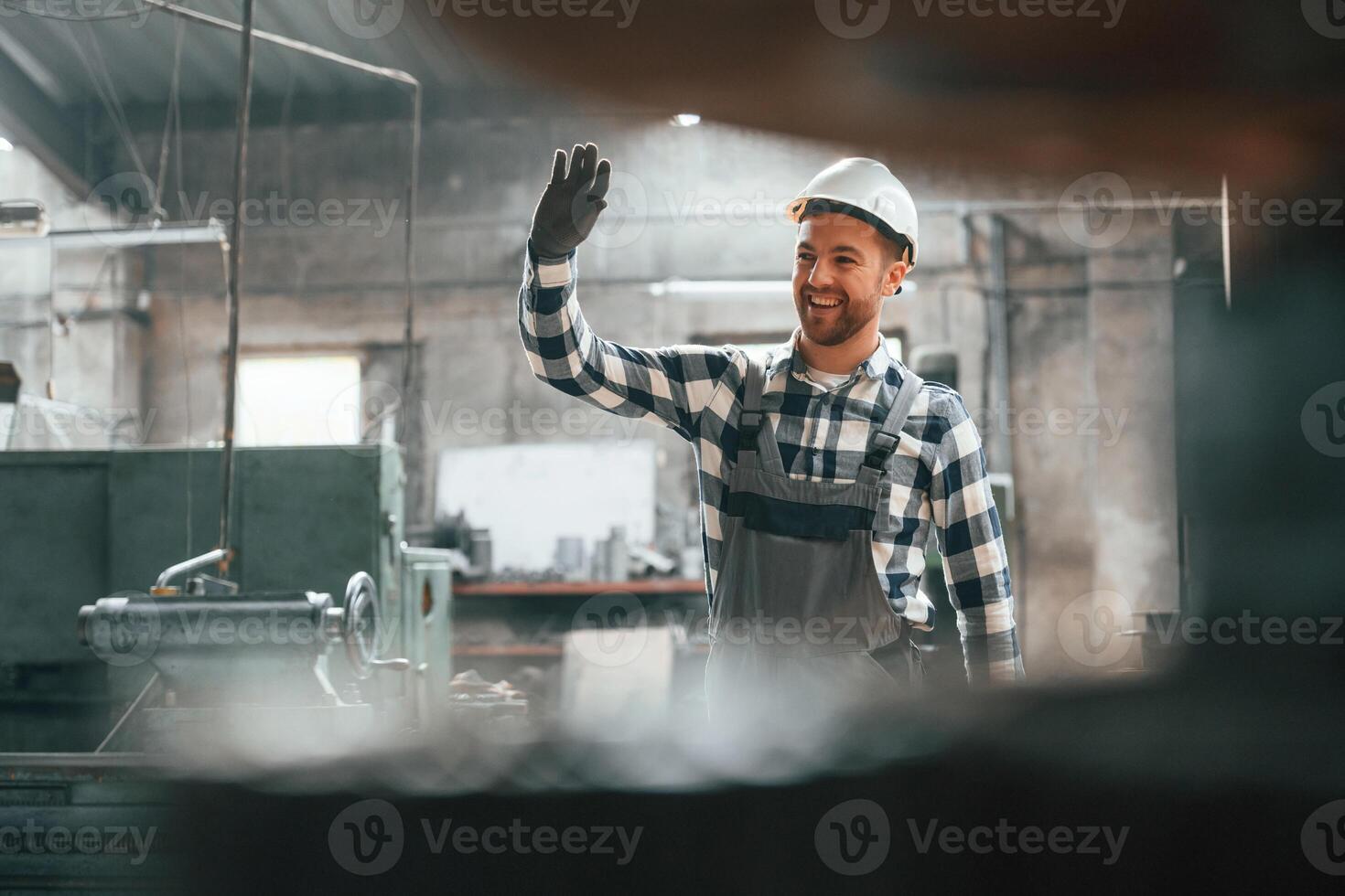 Front view. Factory male worker in uniform is indoors photo