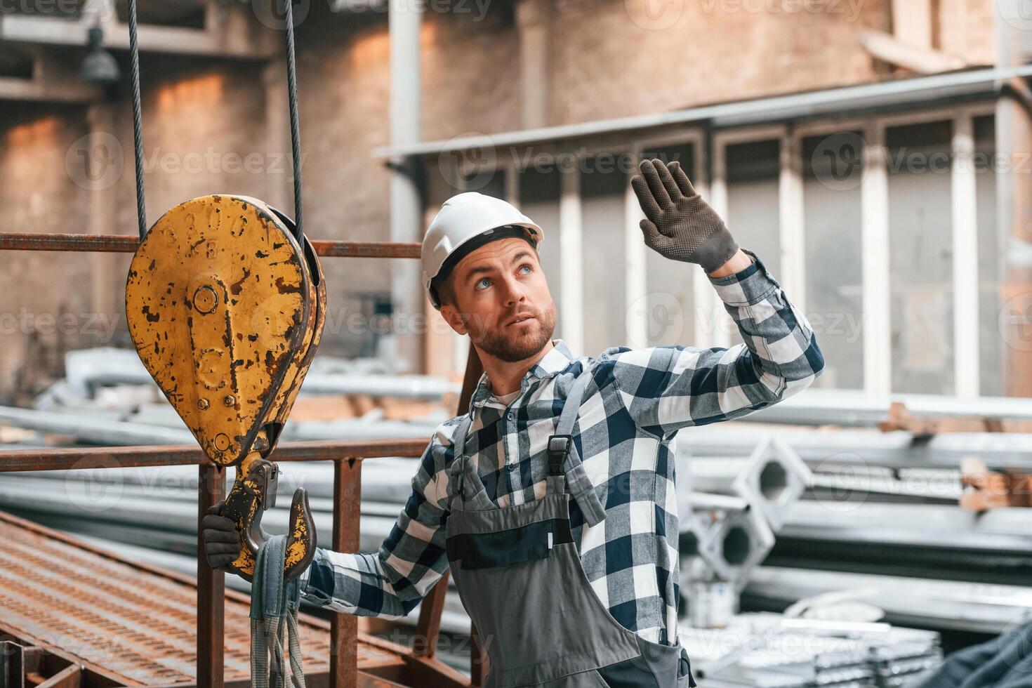 Communicate with ,crane operator. Factory male worker in uniform is indoors photo