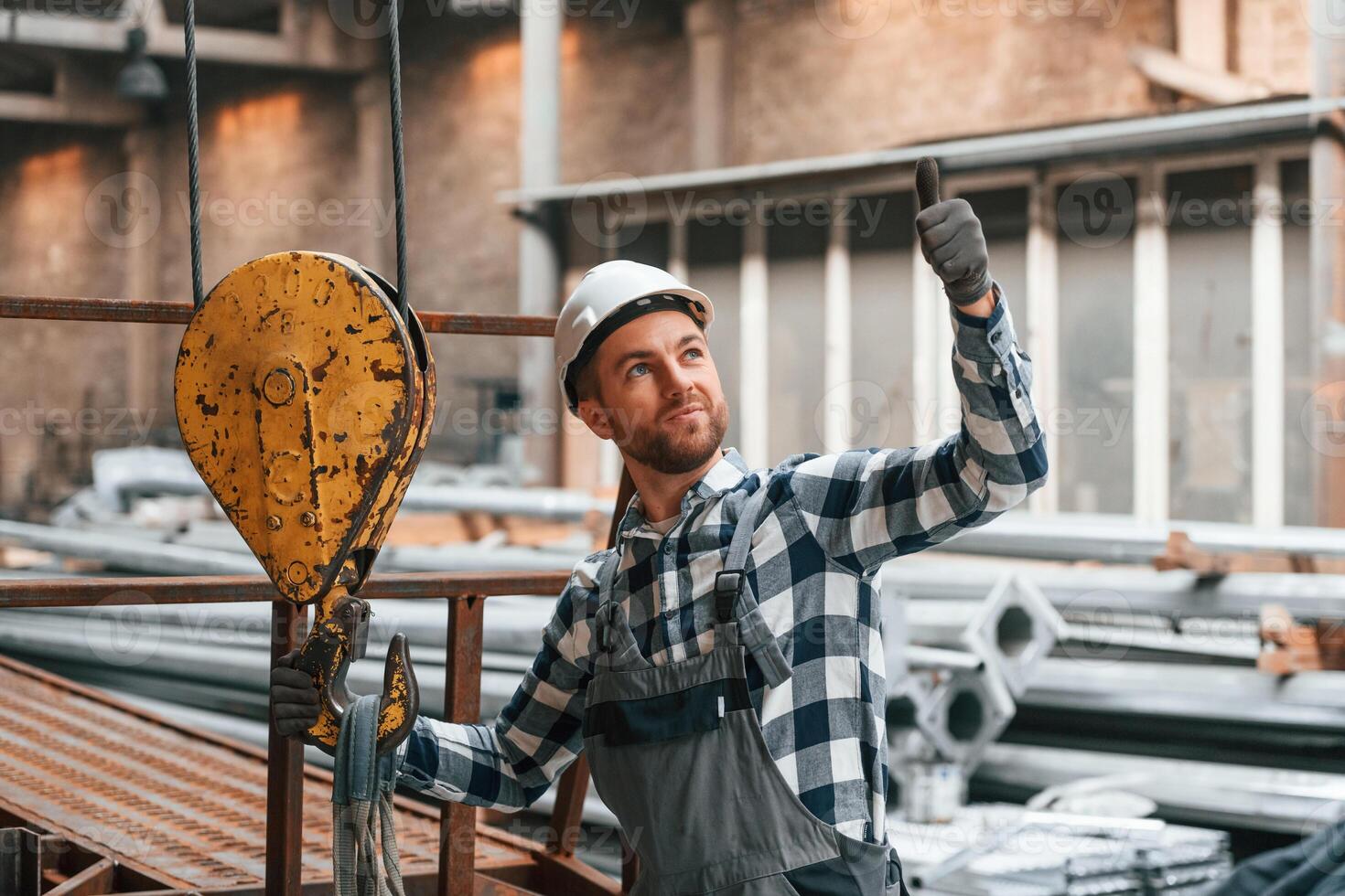 Communicate ,with ,crane operator. Factory male worker in uniform is indoors photo