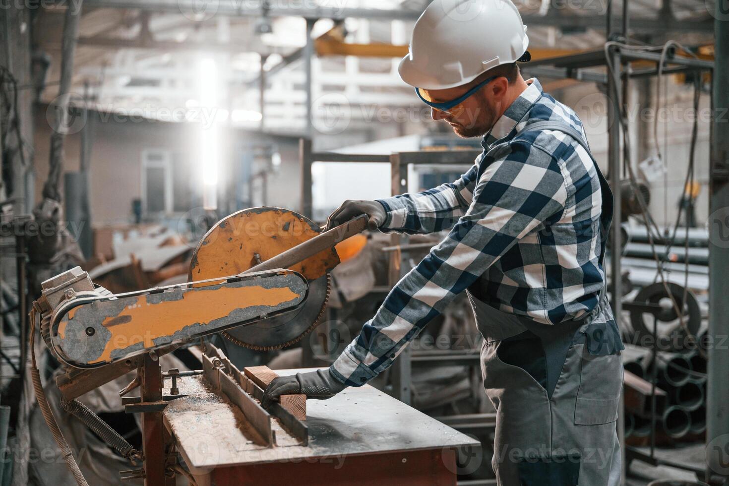 Working by operating machine. Factory worker in uniform is indoors photo