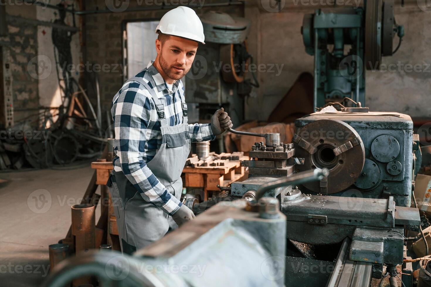 Side view.. Operating the machine. Factory male worker in uniform is indoors photo