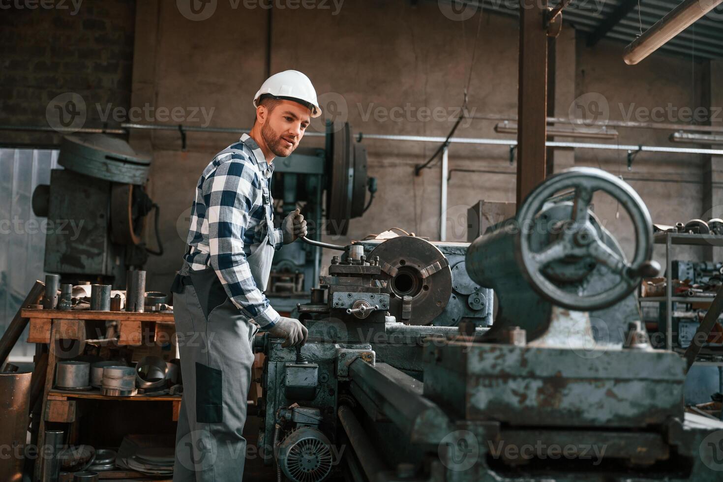 Side view.. Operating ,the machine. Factory male worker in uniform is indoors photo