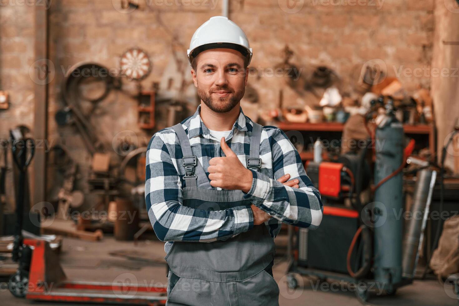 Many objects ,behind. Factory male worker in uniform is indoors photo