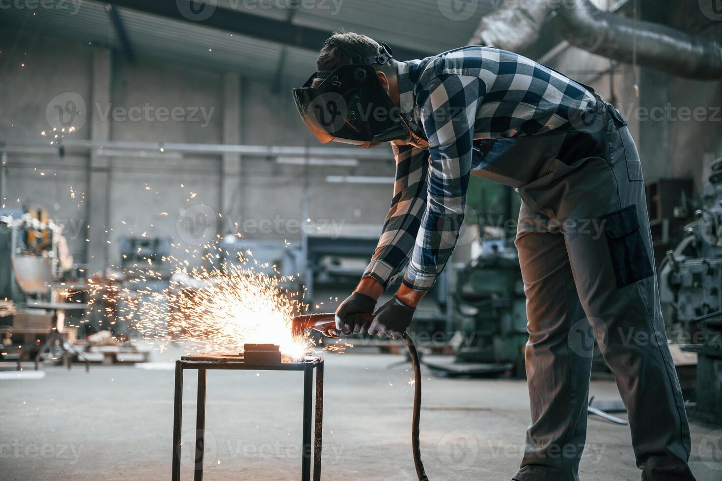 Welding of the iron. Factory male worker in uniform is indoors photo