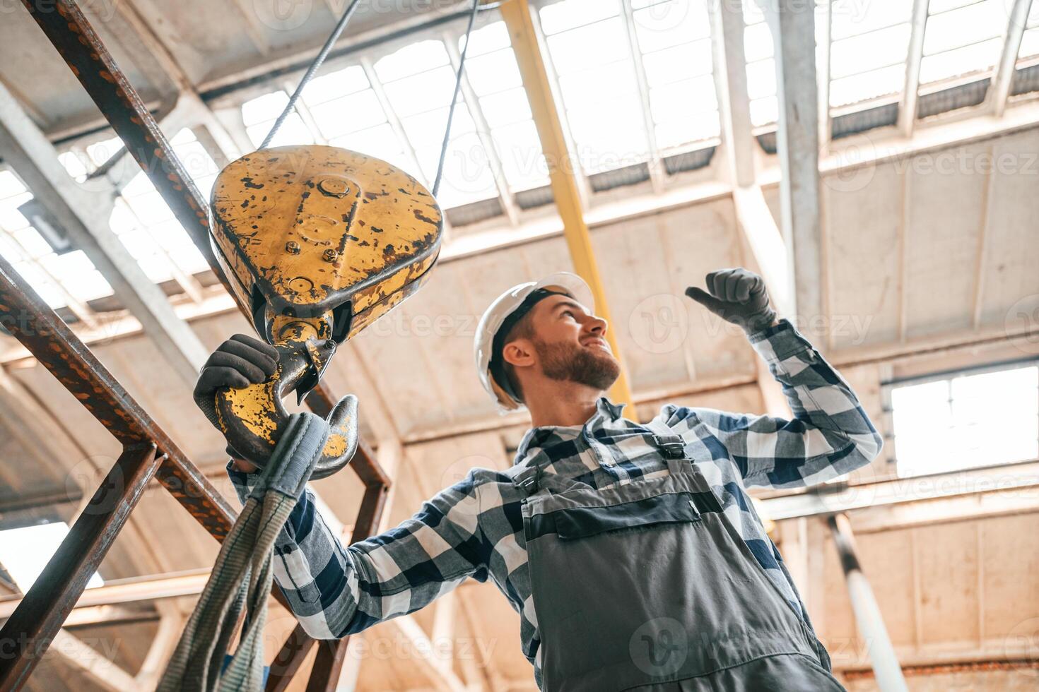 Working with crane. Man in a, factory in uniform is indoors photo