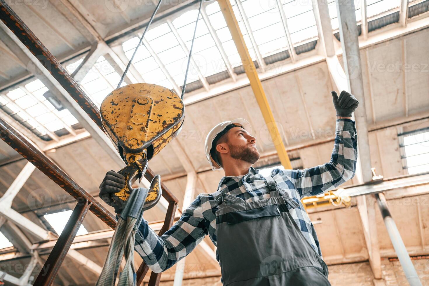 Working, with crane. Man in a factory in uniform is indoors photo