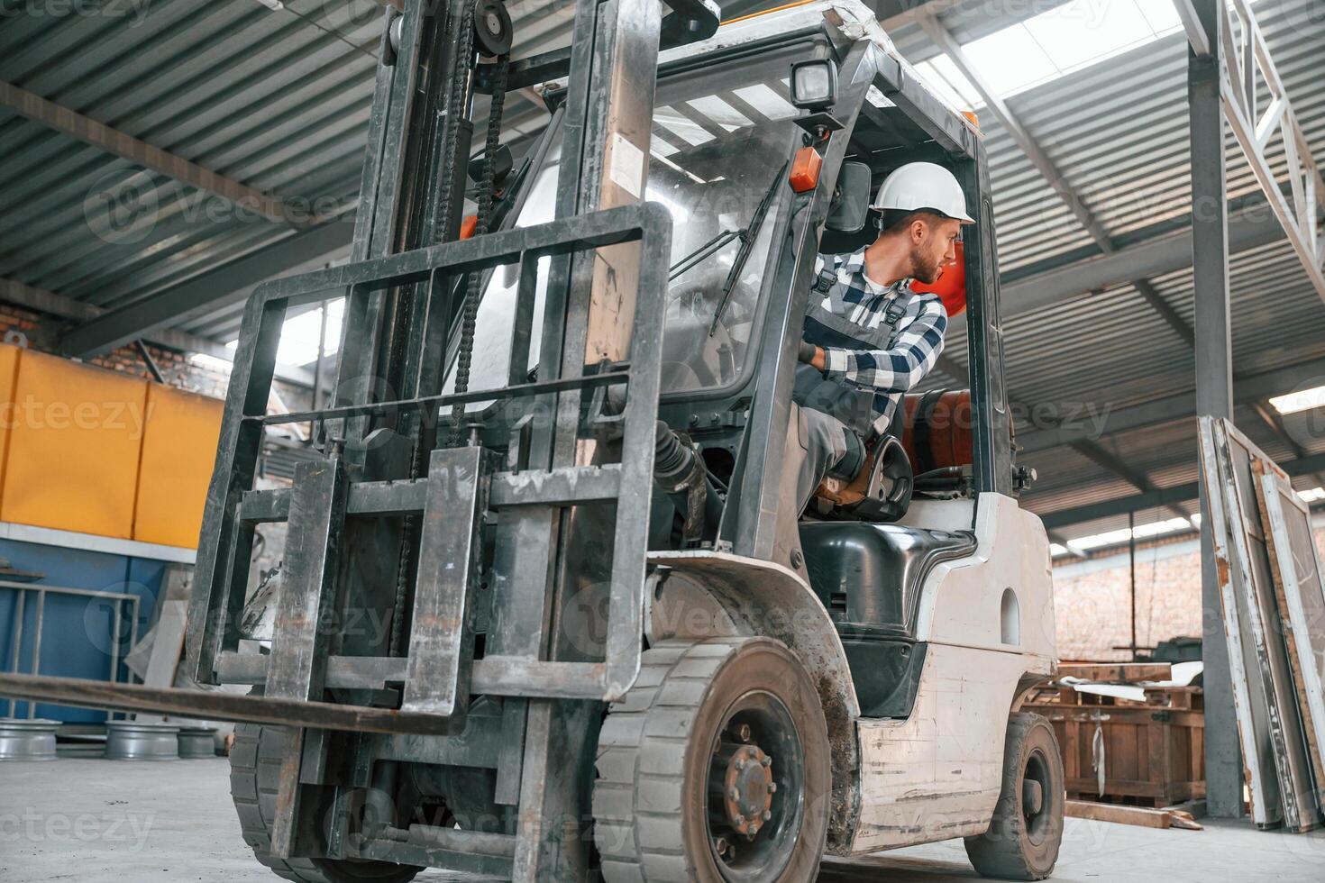 Inside of the forklift. Factory male worker in uniform ,is indoors photo