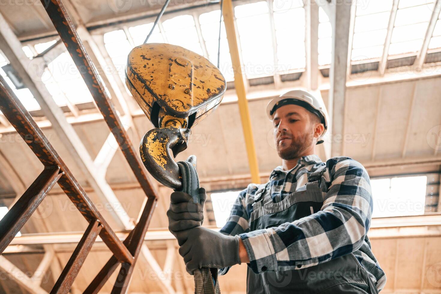 Working with crane. Man ,in a factory in uniform is indoors photo