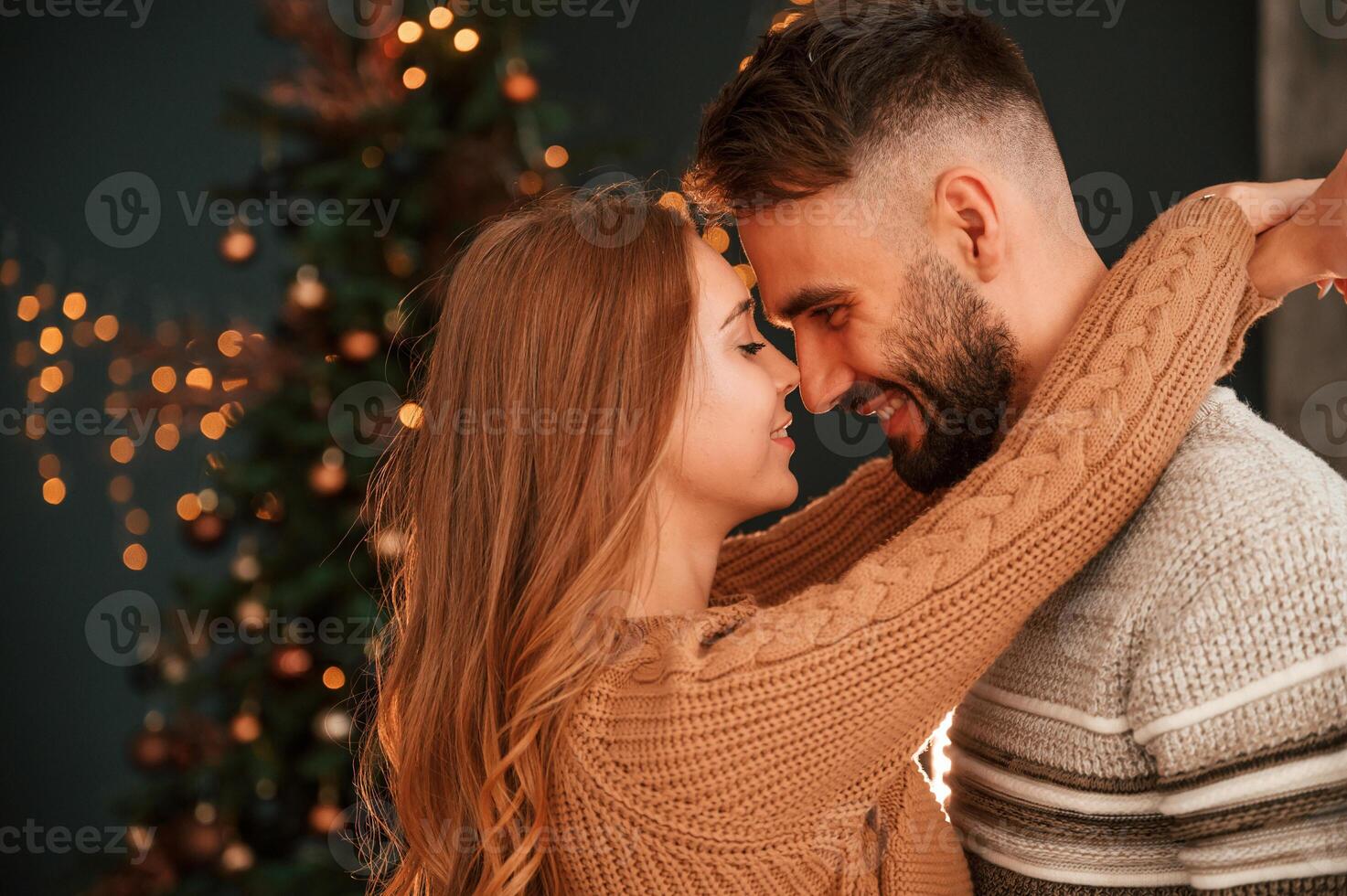 Side view.. Standing and embracing each other. Lovely young couple are celebrating New Year at home photo