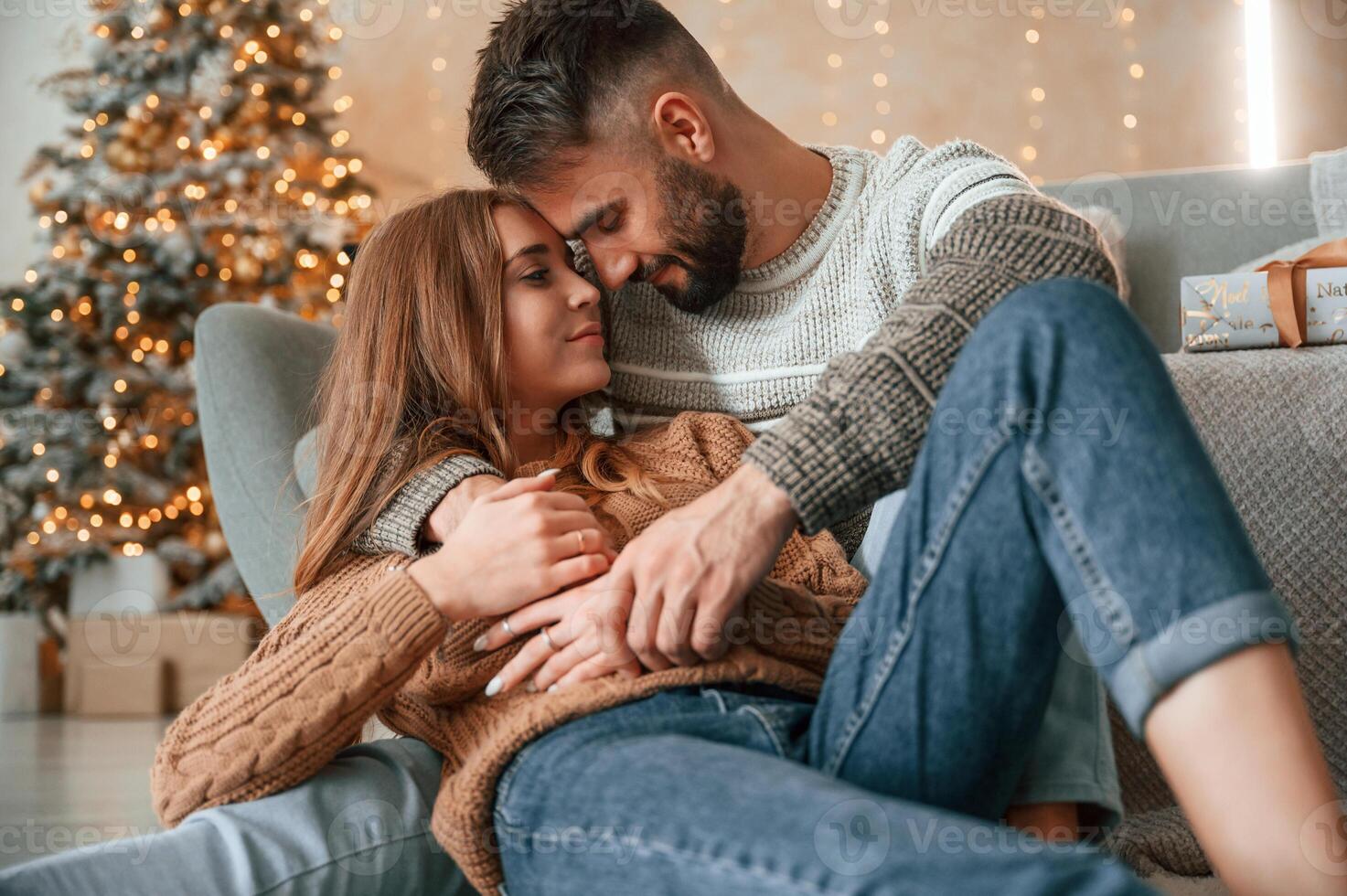 Laying down, on the sofa and embracing. Lovely young couple are celebrating New Year at home photo