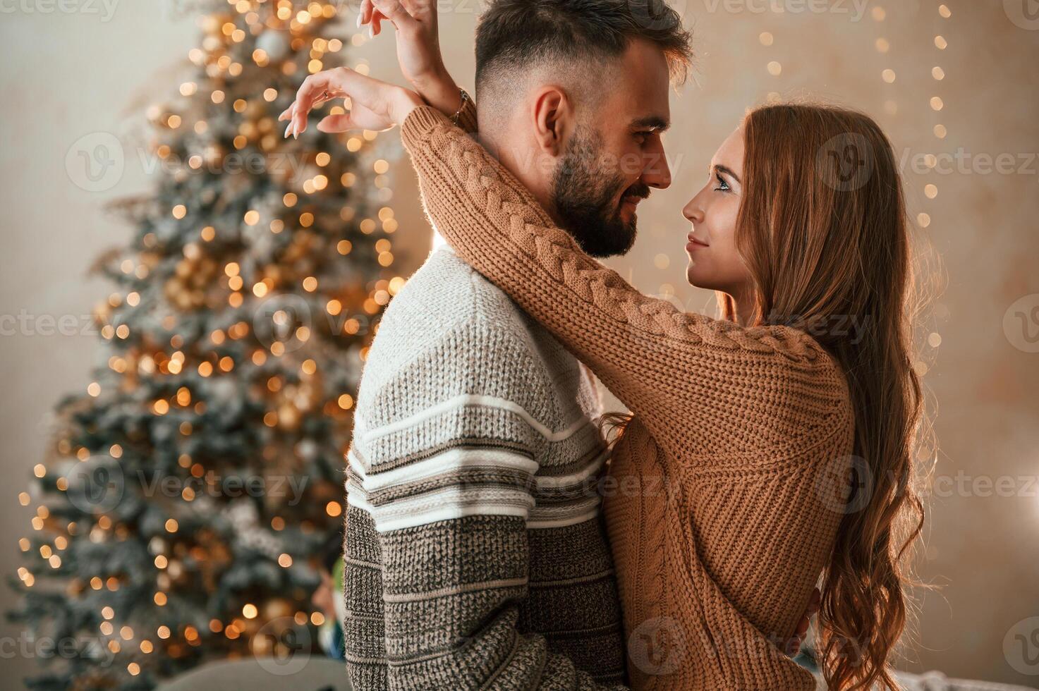 Side, view. Standing and embracing each other. Lovely young couple are celebrating New Year at home photo