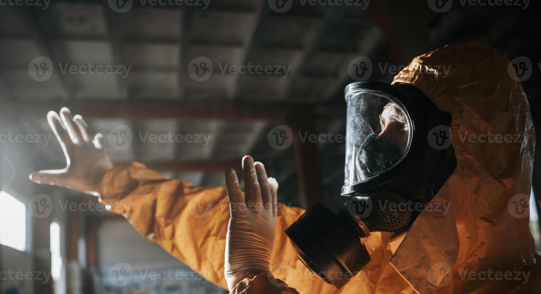 Light from ,nuclear explosion. Man dressed in chemical protection suit in the ruins of the post apocalyptic building photo
