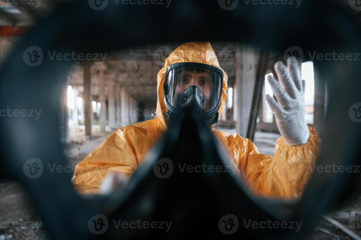 First person, view through respirator. Man dressed in chemical protection suit in the ruins of the post apocalyptic building photo